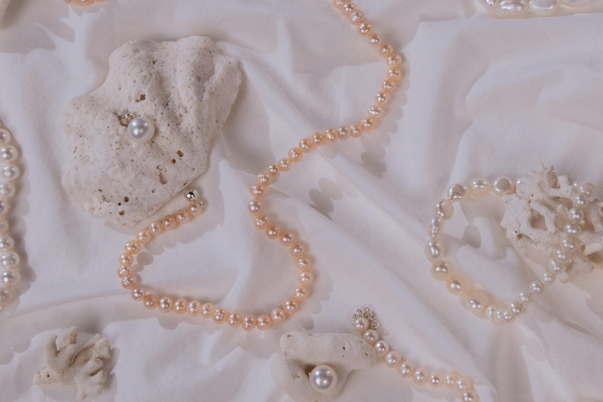 Naszyjniki i kolczyki z pereł na jasnym materiale